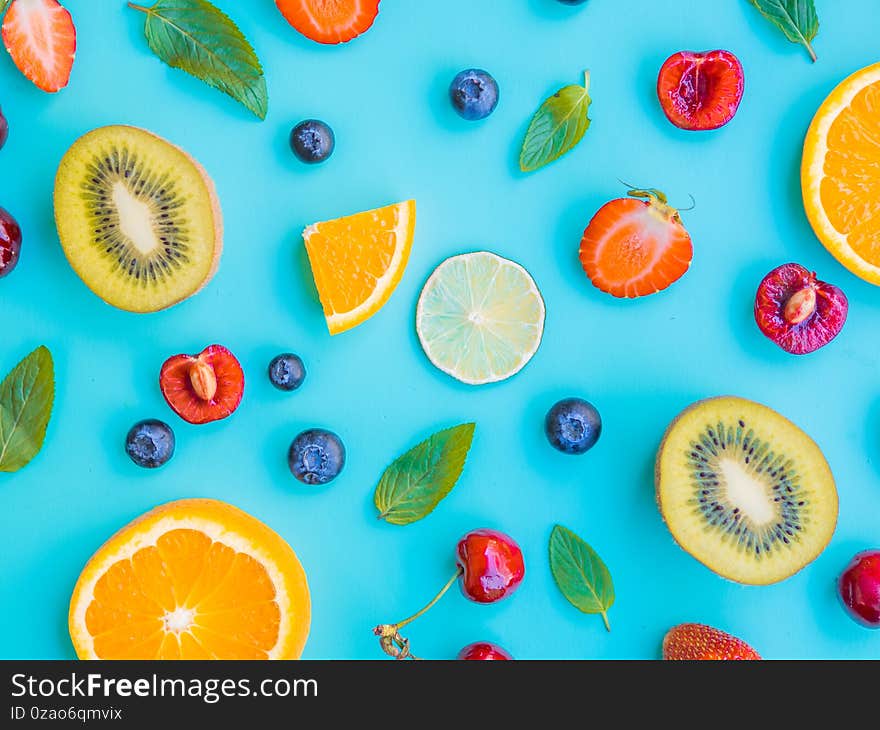 Different fruits and basil green leaves isolated on blue