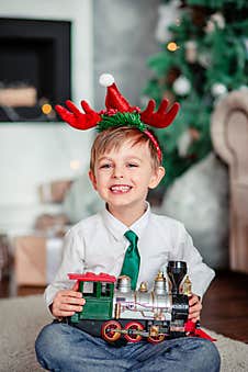 Good Morning. Happy Little Boy With A Gift, Toy Train, Under The Christmas Tree On New Year`s Morning. Time To Fulfill Wishes Royalty Free Stock Photo