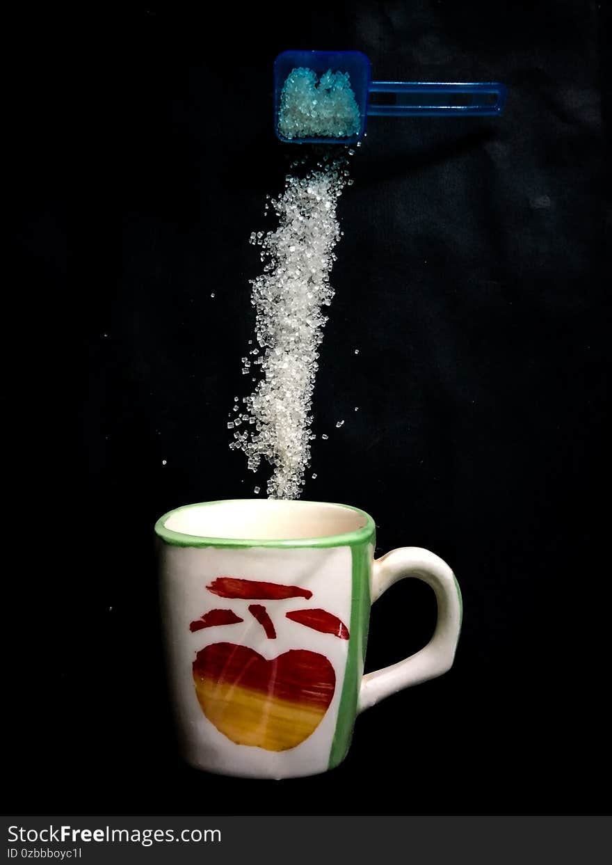 Coffee cup and pouring sugar spoon