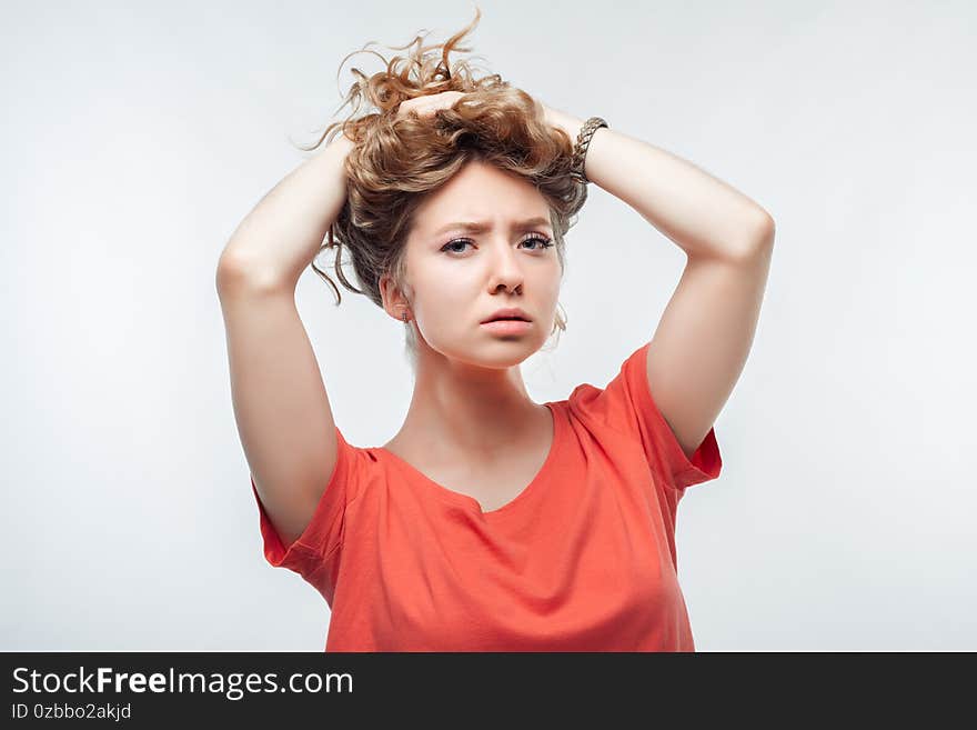 Image of stressed blonde girl with curly hair in casual t shirt grabbing her head. Emotional helplessness. Problems, surprise, fear, fobia concept. Studio shot, white background. Image of stressed blonde girl with curly hair in casual t shirt grabbing her head. Emotional helplessness. Problems, surprise, fear, fobia concept. Studio shot, white background