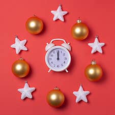 New Year`s Circular Composition Of A Clock In The Center, Snow-white Stars And Golden Toys On A Red Background. Stock Photography