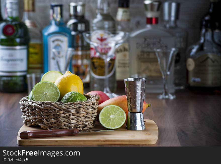 Detail of the bar counter with some fruits in a wicker basket, knife and drink dispenser. Blurred background, copy space