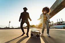 Young Afro Friends Wearing Face Mask Dancing Outdoor While Listening To Music With Wireless Headphones And Boombox Royalty Free Stock Images