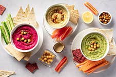 Various Hummus Dips In Bowls, Served With Fresh Vegetables And Crisps. Stock Images