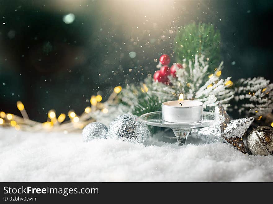 Christmas decoration with candles, fir branch and balls on snow