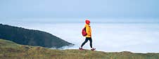 Young Female Backpacker Dressed Orange Waterproof Jacket Hiking By The Mountain Above The Cloud Route At The End Of February On Royalty Free Stock Images