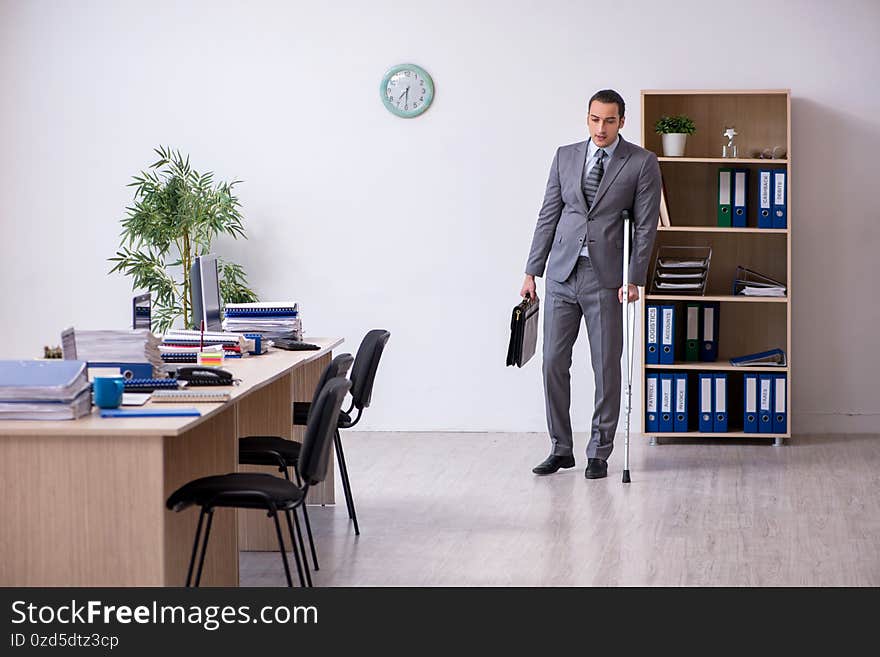 Young leg injured male employee working in the office