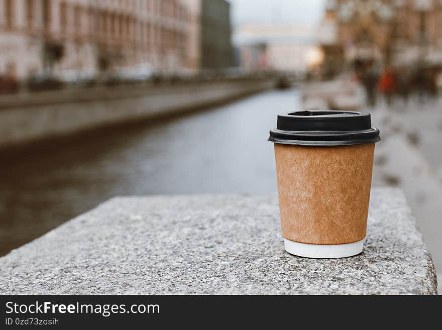 Paper cup of natural coffee on bridge near of river in St. Petersburg, copy space