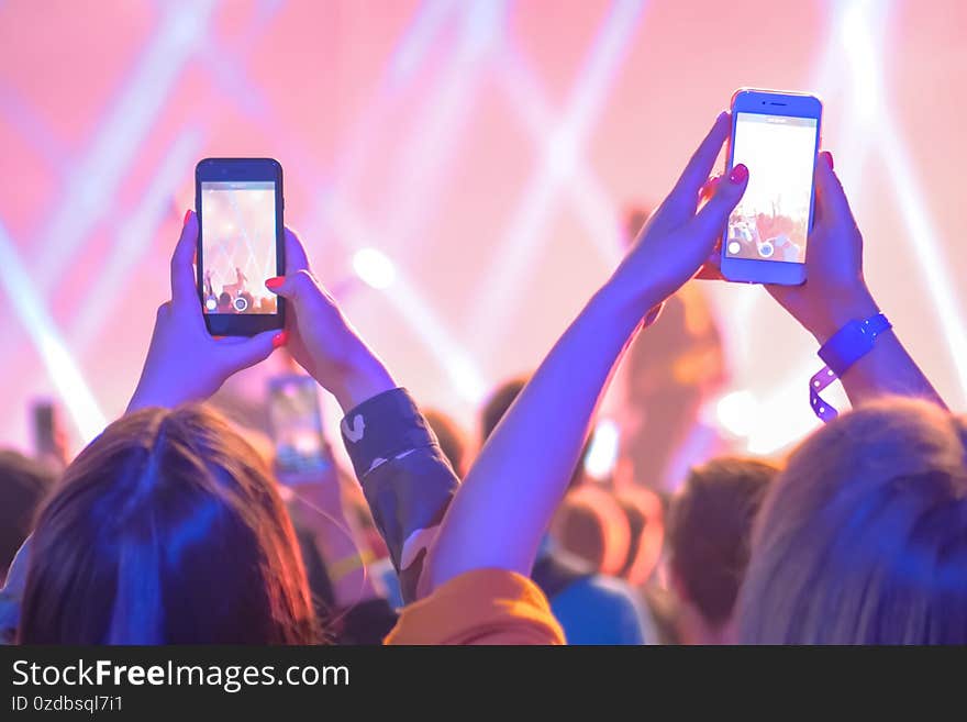 Teenagers taking photo or recording video of live music concert with smartphone. Bright colorful stage lighting. Nightlife, technology, photography, entertainment concept. Teenagers taking photo or recording video of live music concert with smartphone. Bright colorful stage lighting. Nightlife, technology, photography, entertainment concept