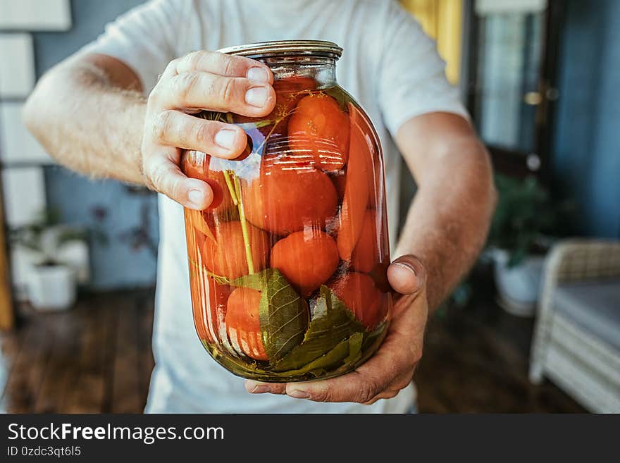 Canning, male hands hold a jar of tomatoes