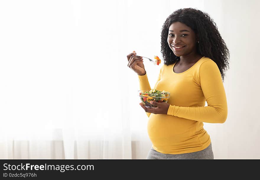 Nutrition and healthy diet during pregnancy. Happy pregnant black woman enjoying fresh vegetable salad at home, panorama with copy space. Cheerful expecting african lady standing by window and eating. Nutrition and healthy diet during pregnancy. Happy pregnant black woman enjoying fresh vegetable salad at home, panorama with copy space. Cheerful expecting african lady standing by window and eating