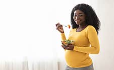 Happy Pregnant Black Woman Eating Fresh Salad At Home Stock Photo