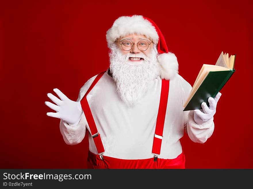 Portrait of his he attractive cheerful cheery funny glad fat white-haired Santa reading book education pulling suspender