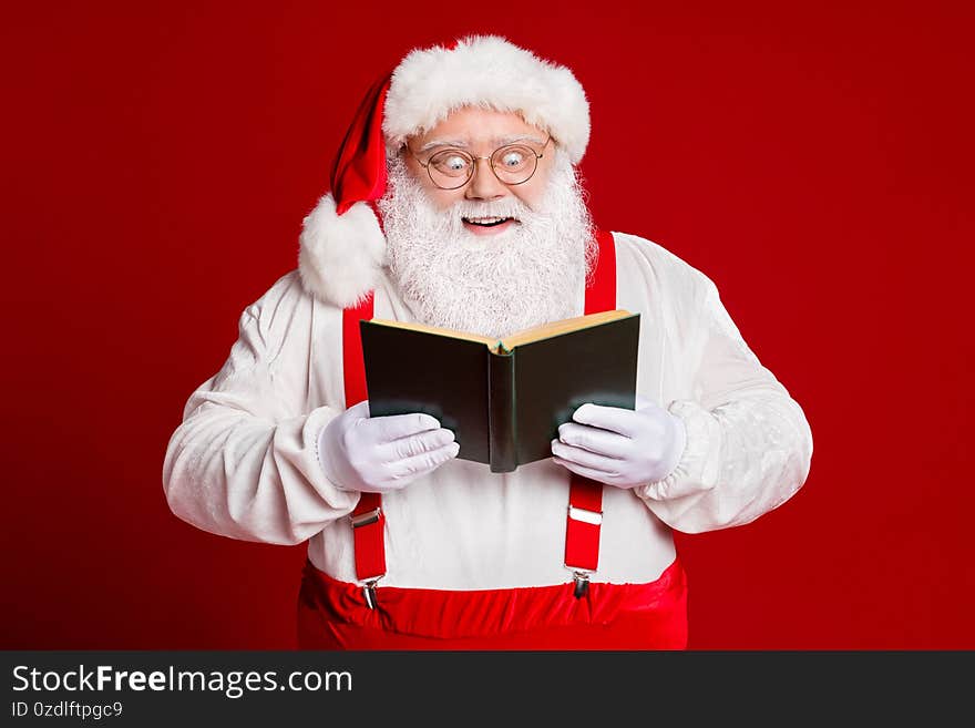 Portrait of his he attractive cheerful cheery funny amazed fat white-haired Santa reading interesting book isolated over