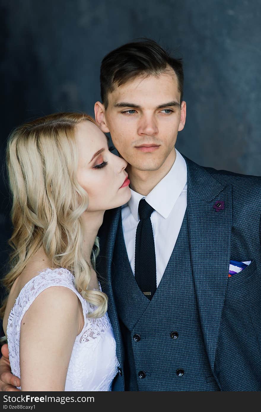 Cute wedding couple in the interior of a classic studio decorated. They kiss and hug each other. Cute wedding couple in the interior of a classic studio decorated. They kiss and hug each other