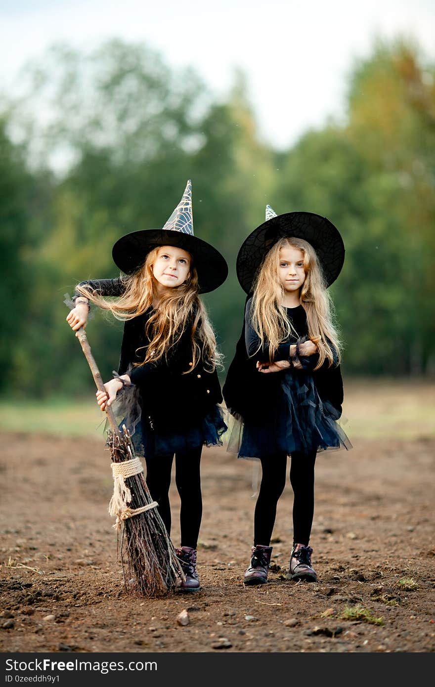 Two girls dressed as witches in the park during halloween