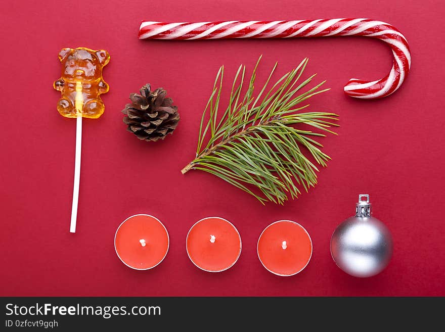 Christmas background red with pine sprig, ornament and candy canes and candles.