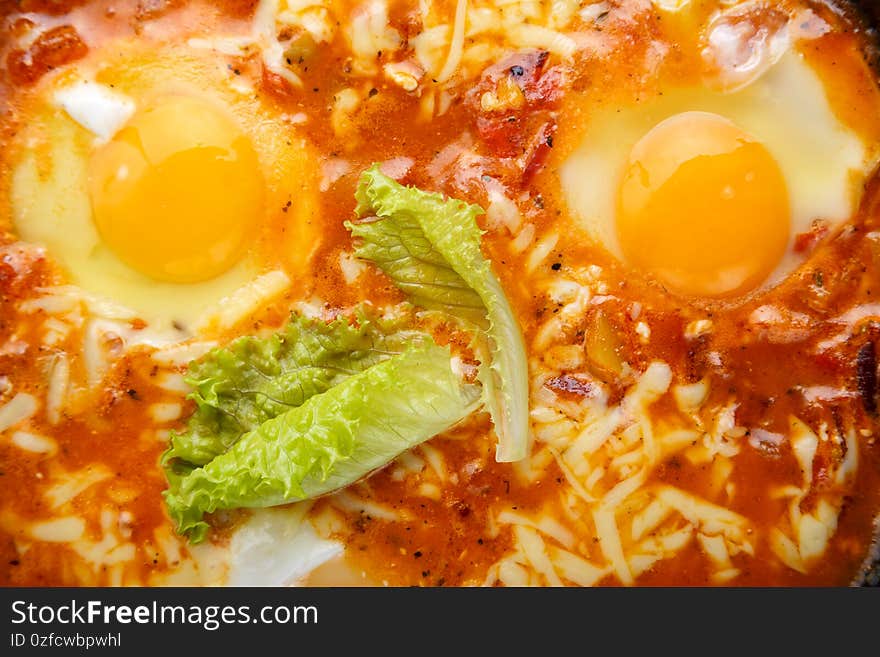 Israeli fried eggs shakshuka with cheese and sauce close-up. horizontal photo