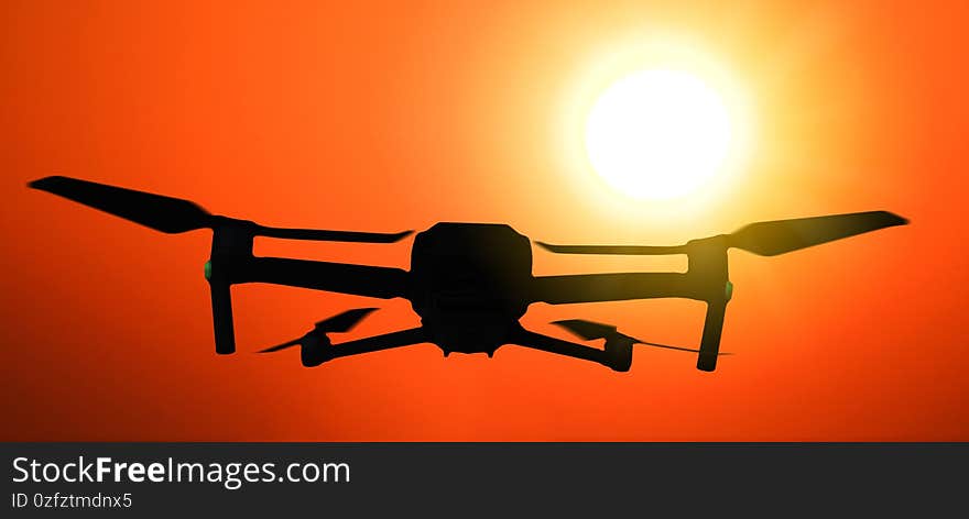 Silhouette of a drone flying in the air at dramatic sunset. Silhouette of a drone flying in the air at dramatic sunset