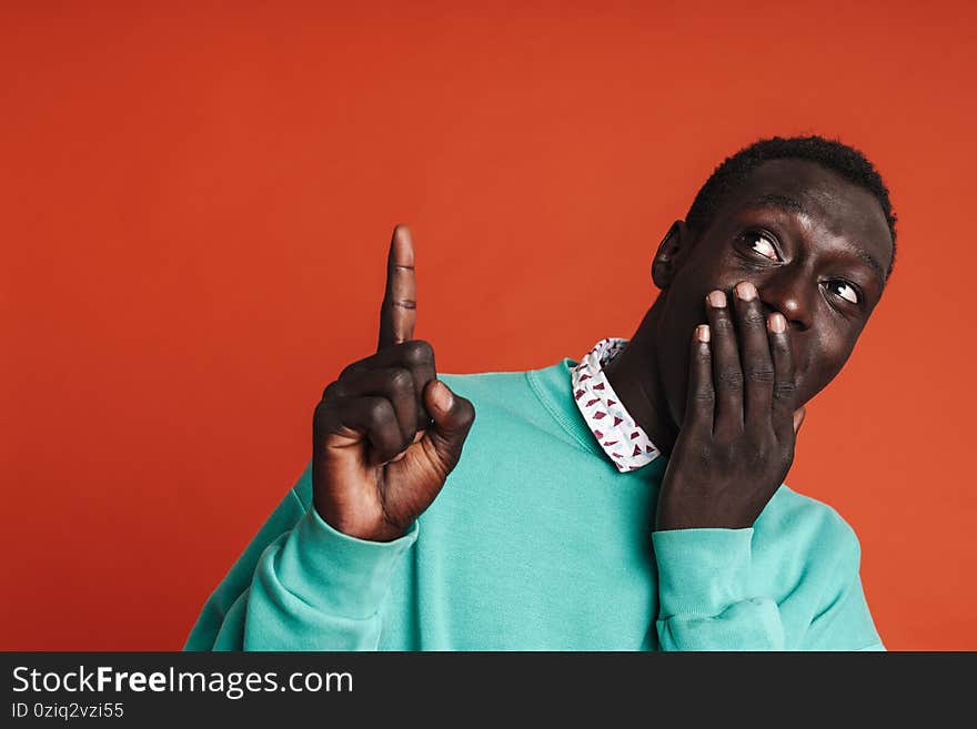 Happy young african man presenting copy space isolated over red background