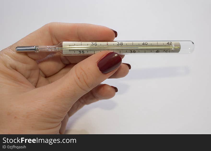 A woman`s hand holds a mercury thermometer for measuring body temperature