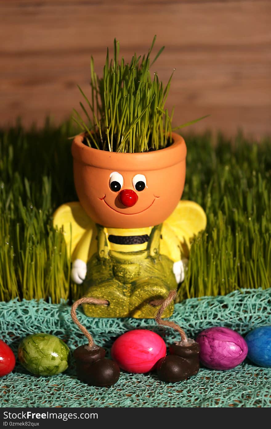 Vertical shot of a funny decoration with grass in a pot and colorful eggs for Easter in a garden