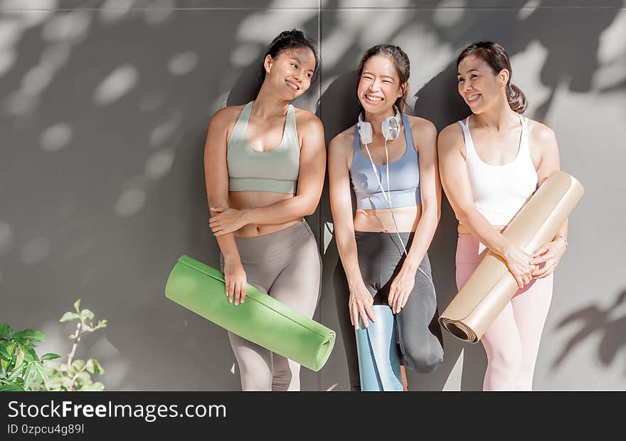 Asian women talking and laughing together after yoga class