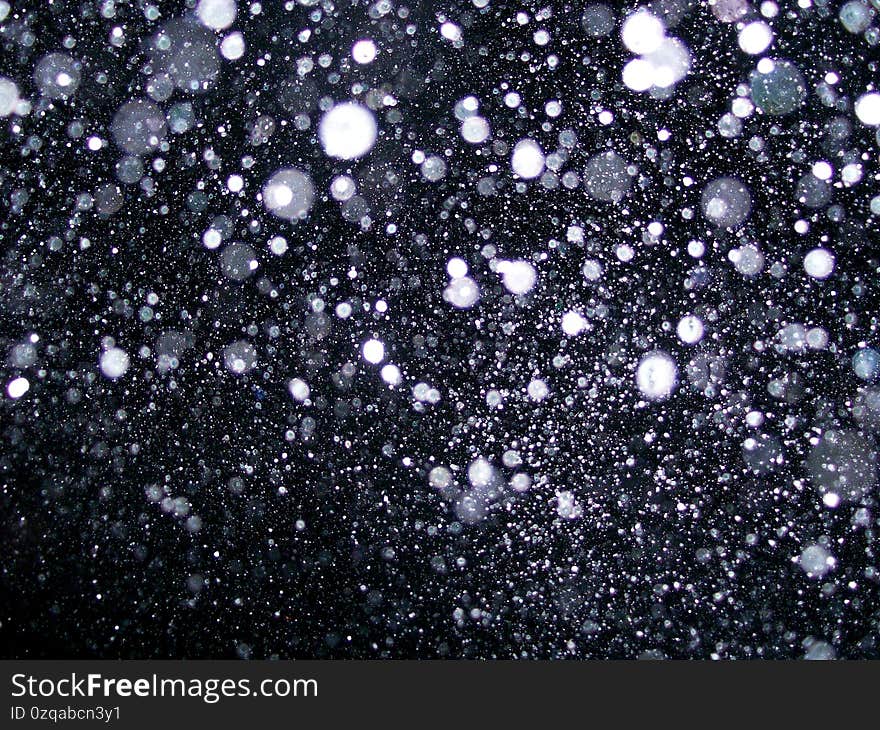 Illuminated sparkling falling snow at night