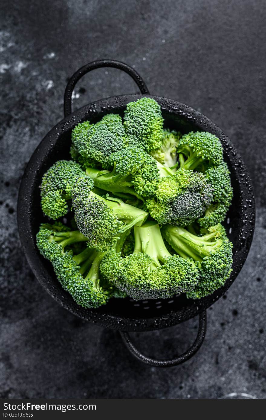 Organic Raw green broccoli cabbage in a colander. Black background. Top view