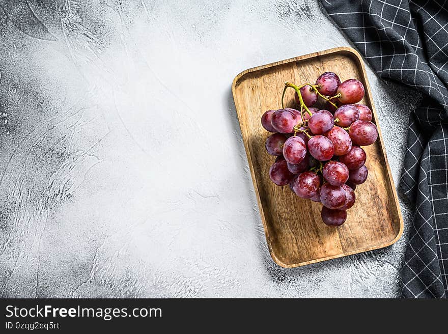 Red ripe grapes in a wooden bowl. White background. Top view. Copy space