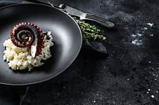 Italian Classic Risotto With Octopus Tentacles. Black Background. Top View. Copy Space Stock Photos