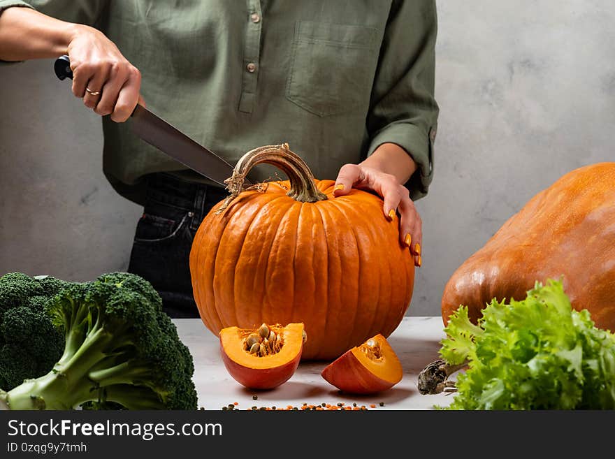 Woman cutting big pumpkin on the kitchen. Close-up.