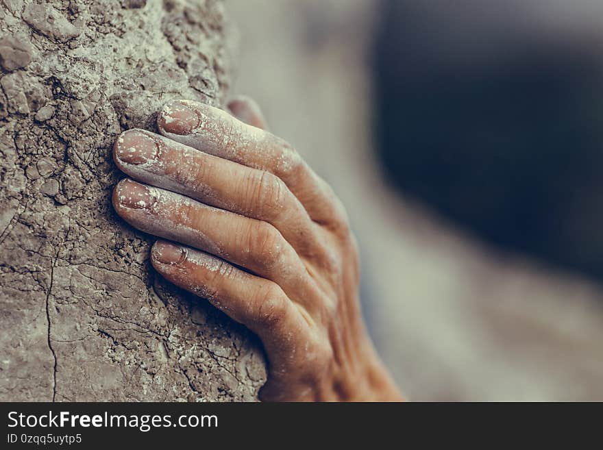 Adult male handholding on to a rock