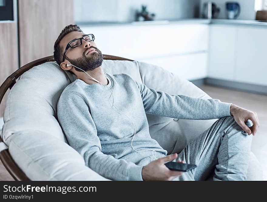 Close up. man enjoying his favorite music,sitting in a chair