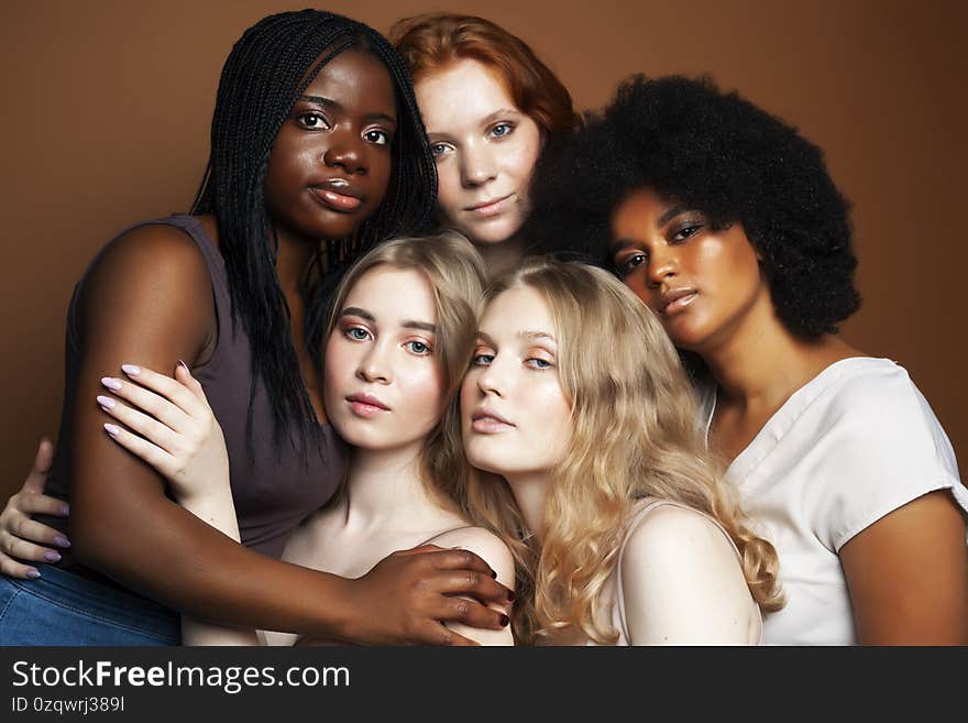 Young pretty african and caucasian women posing cheerful together on brown background, lifestyle diverse nationality people concept close up