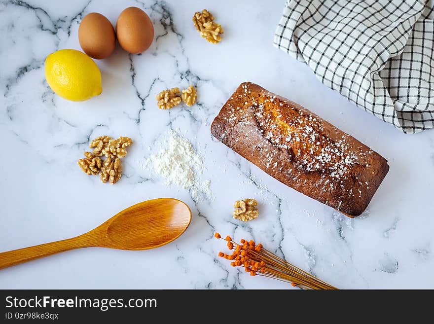 Closeup shot of a baked cake with walnuts lemon and eggs on the table