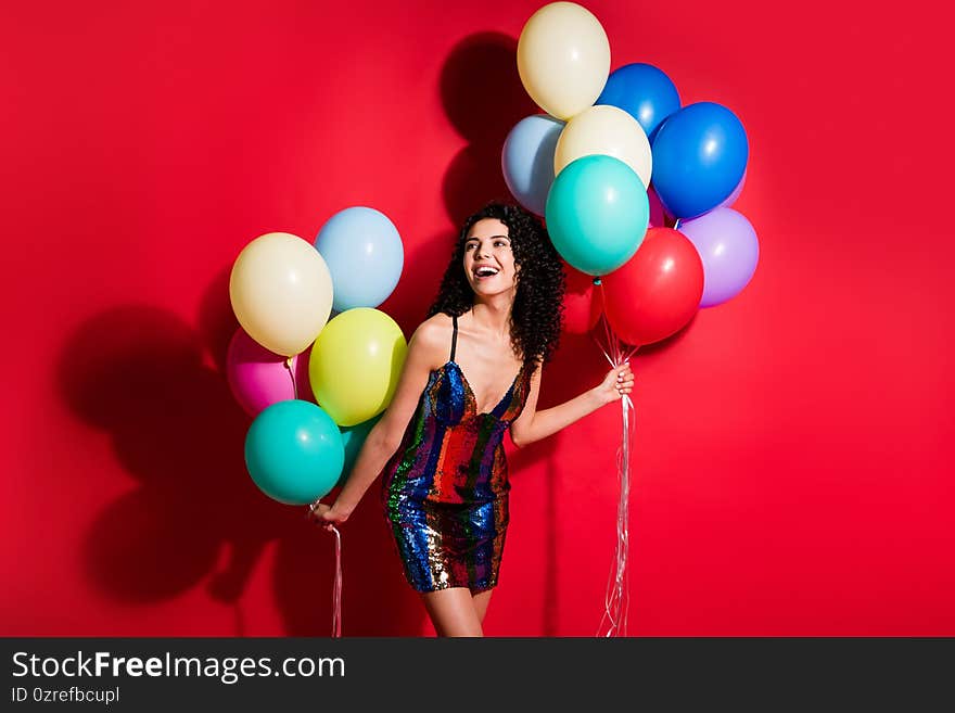 Photo of charming girl hold many balloons look empty space wear glossy short dress isolated vivid red color background