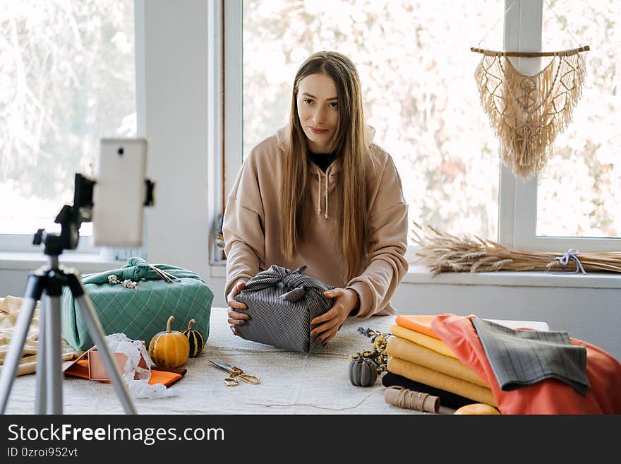 Woman wraps Furoshiki gift in zero waste style and record vlog, master class on cell phone. Furoshiki Japanese Gift