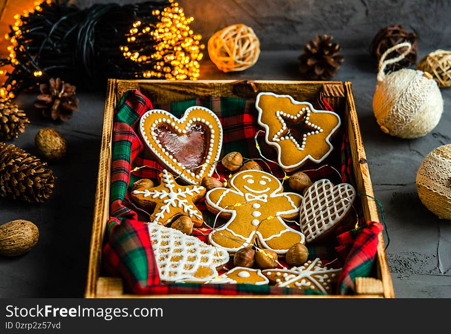 Christmas gingerbread cookies decorated with sugar white icing in a wooden box on a dark background, Christmas garland Christmas toys. Holiday concept for Christmas and New Year. 2021, close-up