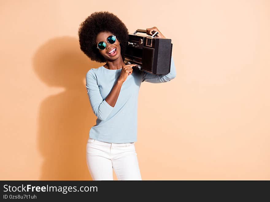 Photo portrait of african american girl pressing play on boom-box isolated on pastel beige colored background