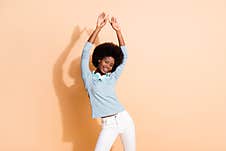 Photo Portrait Of African American Woman Dancing With Both Hands In Air Isolated On Pastel Beige Colored Background Royalty Free Stock Images