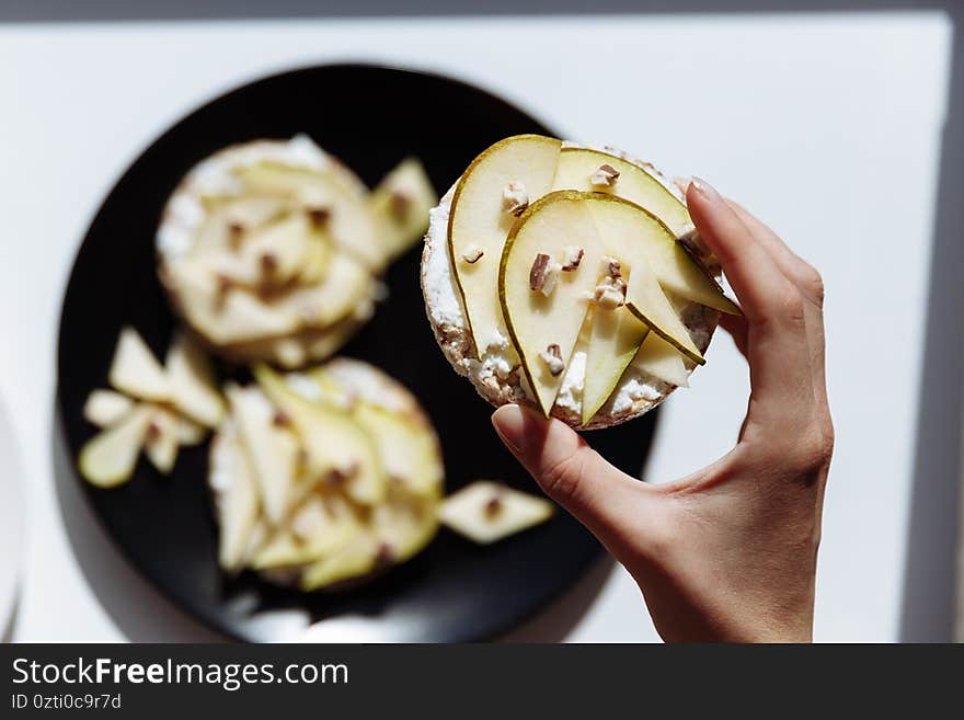 The woman s hand is lying near a homemade fruit cake for breakfast on the ceramic plate. Top view. selective Focus