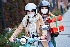 Two Women Wearing Masks And Holding Shopping Bags On Scooter Stock Image