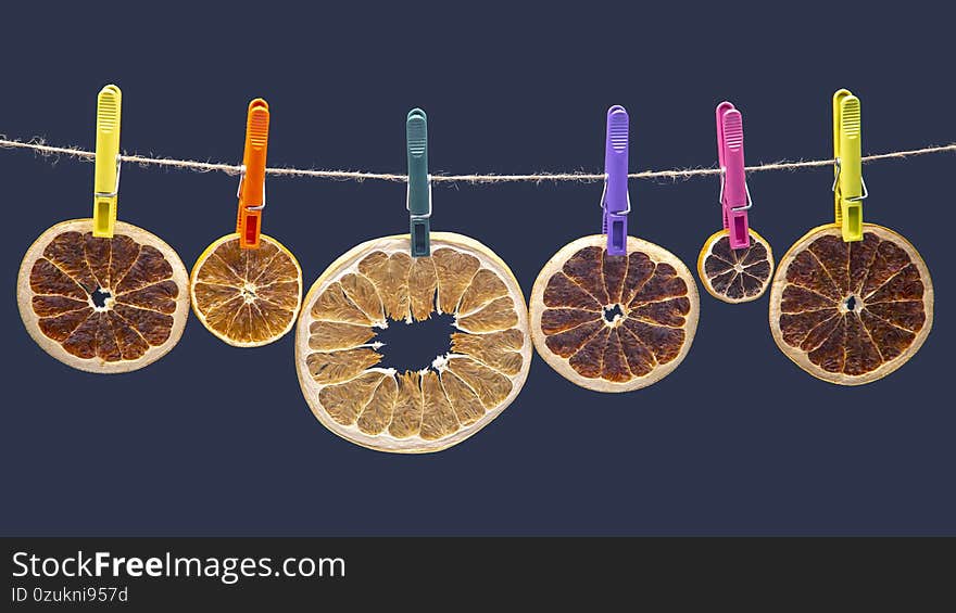 Dried pieces of different citrus fruits hang on colored clothespins