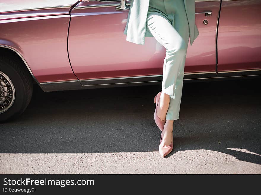 Cropped view of elegant woman standing near retro car on road. Cropped view of elegant woman standing near retro car on road