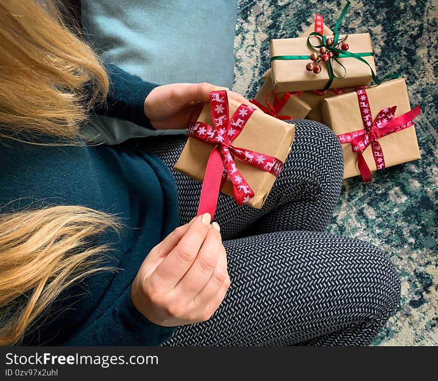 Close up on woman opening christmas present box with more gifts on background