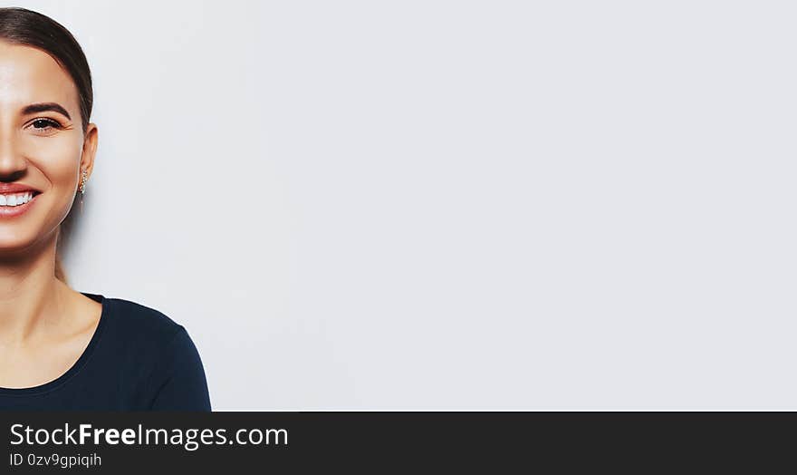 Half face of young smiling girl on white background with copy space.