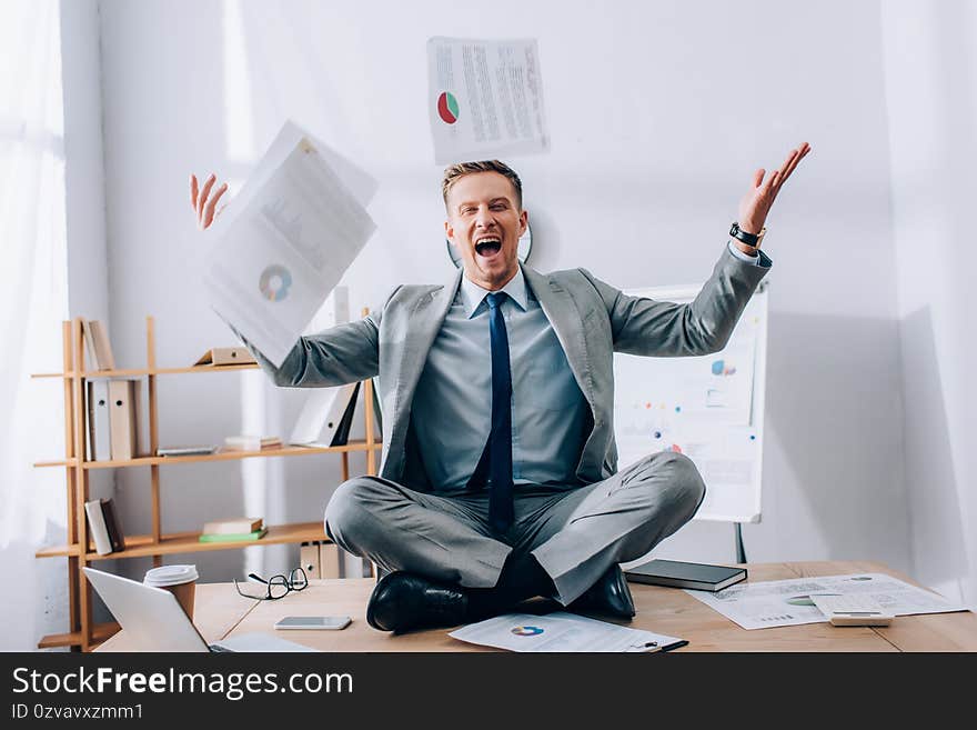 Businessman throwing papers while sitting near