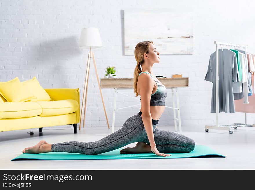 Side view of blonde sportswoman practicing yoga with closed eyes on fitness mat