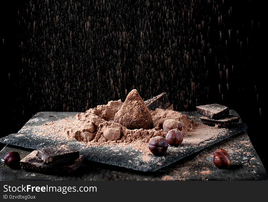 Chocolate truffle sprinkled with cacao and golden powder against the black background